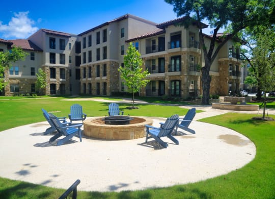 an outdoor firepit with adirondack chairs in front of an apartment building