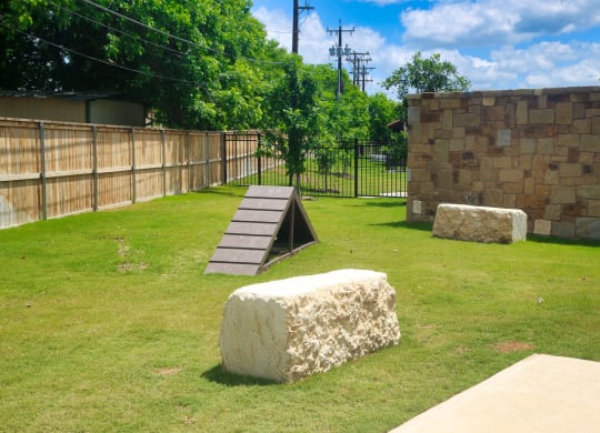 a ramp in a grassy area with a stone wall and trees in the background