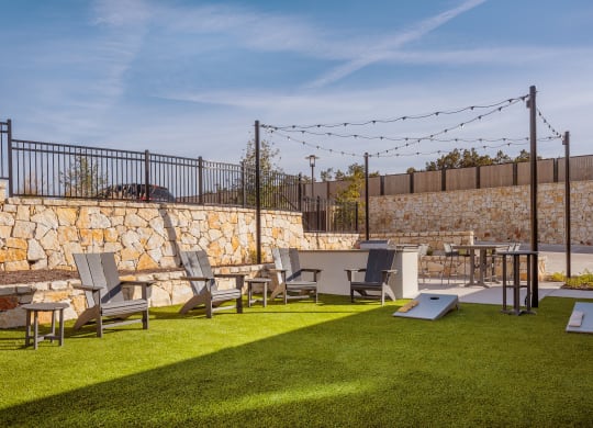 a backyard with lawn chairs and tables and a stone wall
