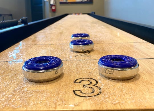 shuffleboard inside the game room at mela's luxury apartments