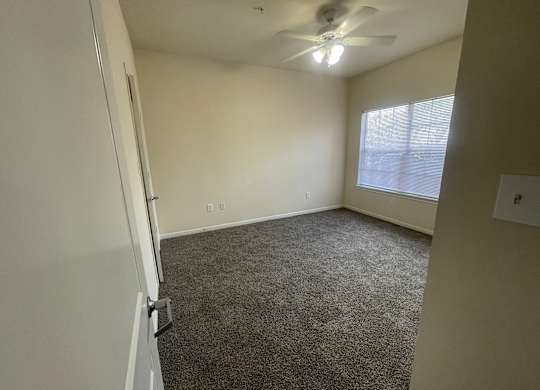 A room with a ceiling fan and carpeted floor.