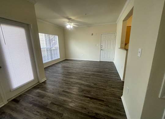 A room with wooden flooring and a window with blinds.