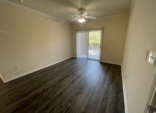A room with a ceiling fan and sliding glass doors.