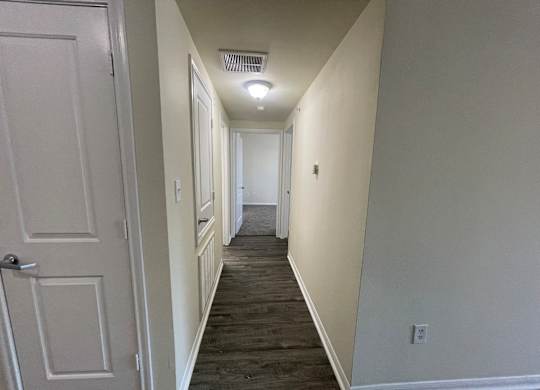 A long hallway with a door on the left and a light on the right.