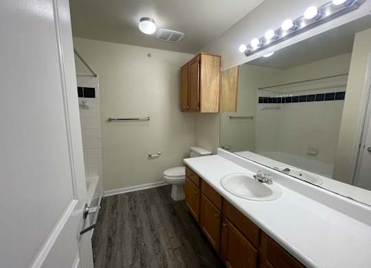 A bathroom with a toilet, sink, and mirror.