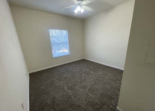 A room with a ceiling fan and a window showing a snowy scene outside.