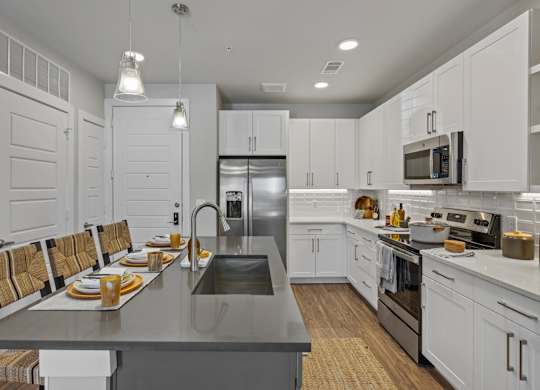 A modern kitchen with a long table set for a meal.