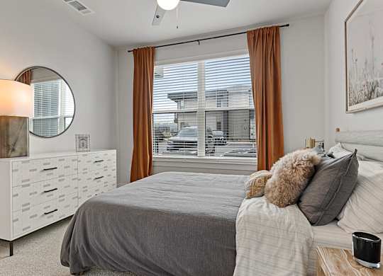A bedroom with a bed, nightstand, and window with curtains.