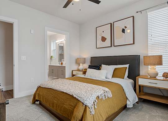 A bedroom with a bed, nightstands, and a ceiling fan.