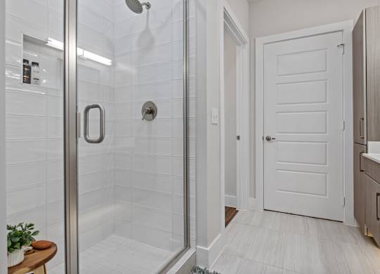 A white door is in a bathroom with a glass shower door.