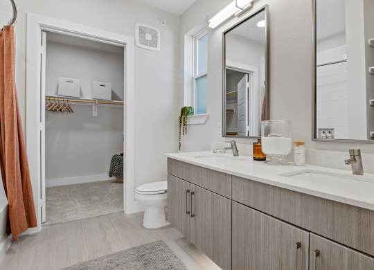 A bathroom with a toilet, sink, and mirror.