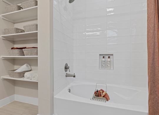 A white bathtub with a towel rack and towels on the shelves.
