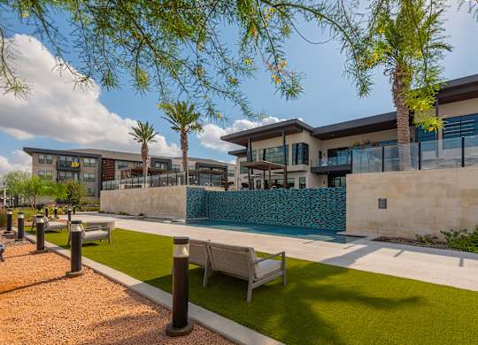 A modern building with a pool and palm trees.