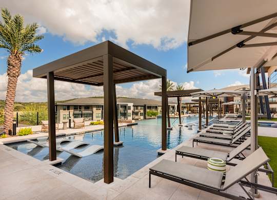 A pool area with sun loungers and a wooden pavilion.