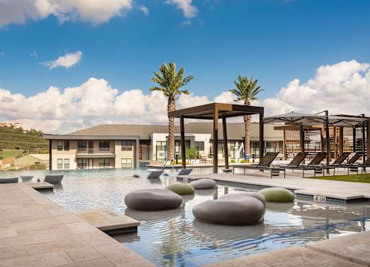 A modern poolside area with a large building in the background.