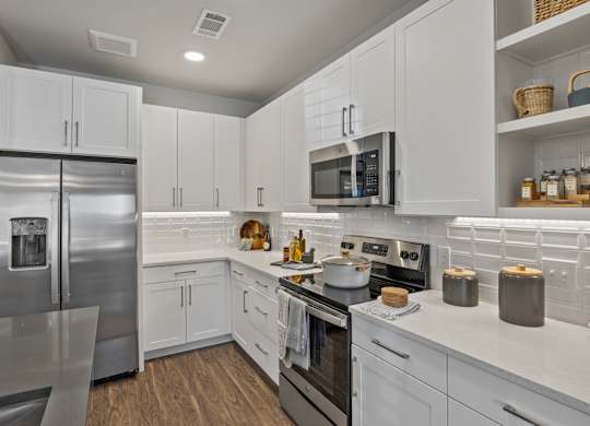 A modern kitchen with white cabinets and stainless steel appliances.