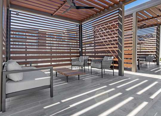 A patio with a couch, chairs, and a table with a ceiling fan.