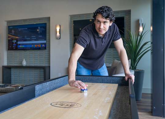 A man is playing shuffleboard in a room.