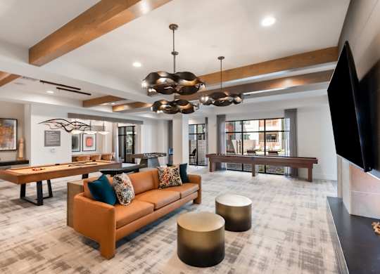 A modern living room with a brown sofa and a television on the right side.