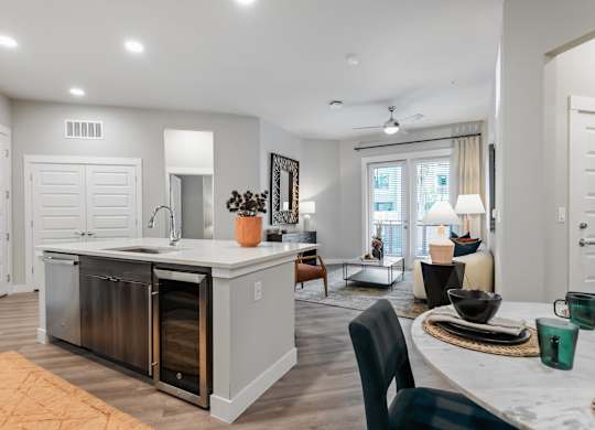 A modern kitchen with a large island and a dining area with a table set for two.