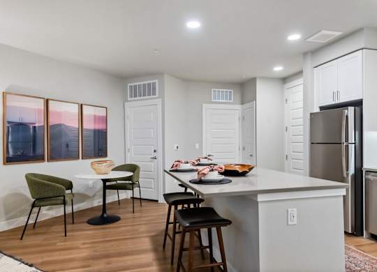 A kitchen with a table and chairs and a refrigerator.