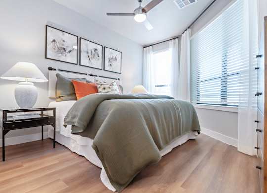 A bedroom with a bed, a nightstand with a lamp, and pictures on the wall.