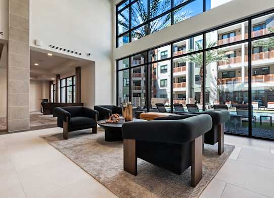 A modern living room with black furniture and a large window.