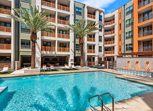 A swimming pool in front of a multi-story apartment building.