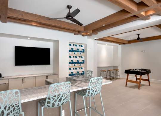 A room with a television, chairs, and a table.
