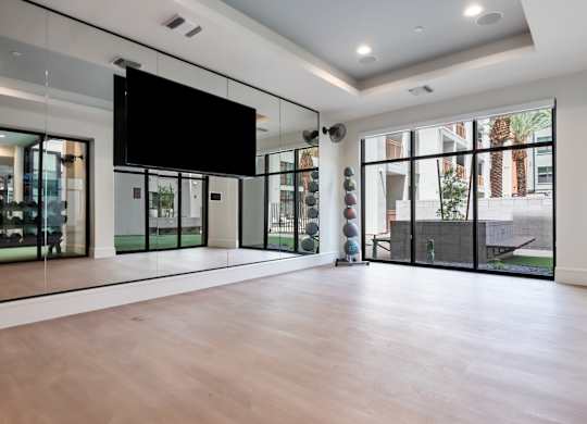 A spacious room with a television mounted on the wall and sliding glass doors.
