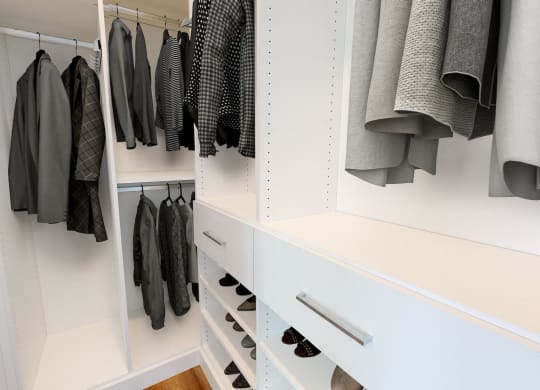 a walk in closet with white cabinets and drawers