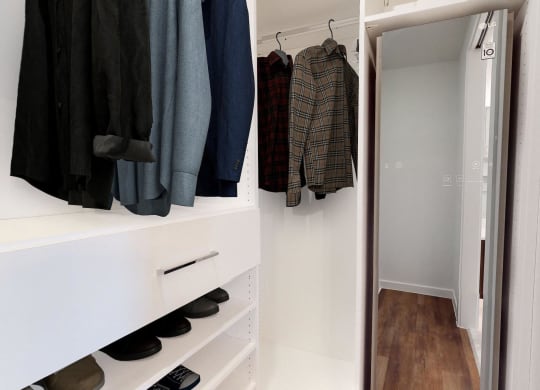 a walk in closet with a mirror and some clothes hanging on the wall