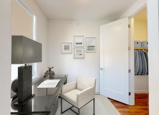 a living room with a desk and chair and a door to a closet