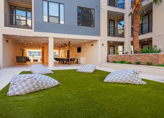 four pillows on a lawn in front of an apartment building