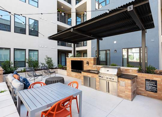 a patio with a barbecue grill and a table with chairs