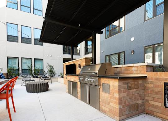 an outdoor kitchen with a grill and a table and chairs
