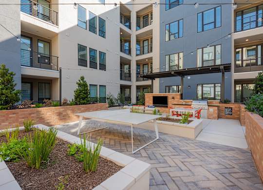 an outdoor living area with a table and chairs in front of an apartment building