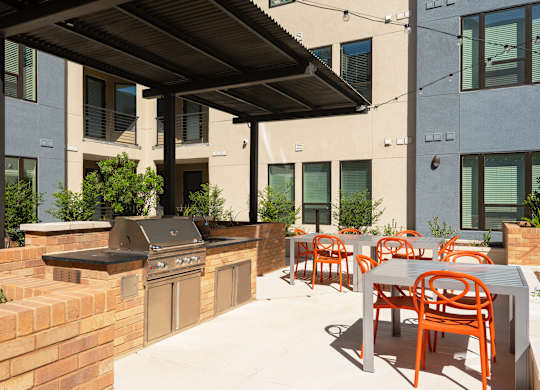 a patio with a barbecue grill and tables and chairs