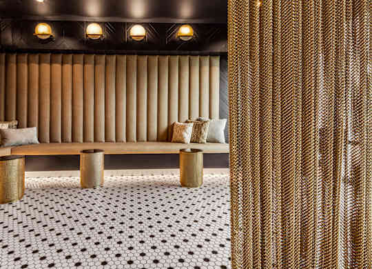 a seating area with a bench and stools on a black and white tiled floor