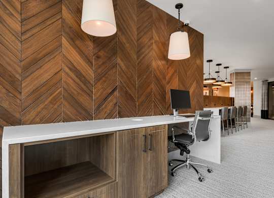a room with a long desk with a computer on it and a wooden wall behind it