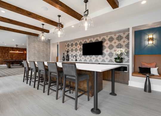 a room with a long table with chairs and a tv on the wall