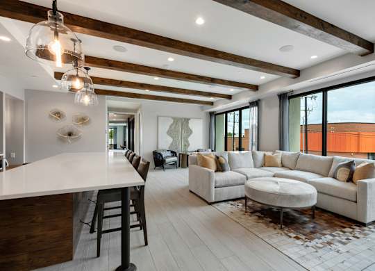 a spacious living room with a large couch and a kitchen with a breakfast bar