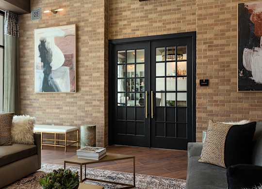 a living room with a black door and a brick wall