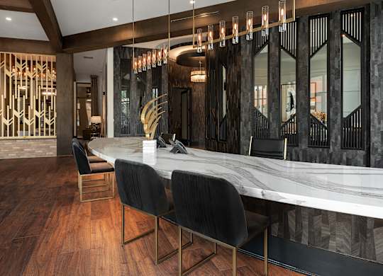 a long marble bar with black chairs and a staircase in the background