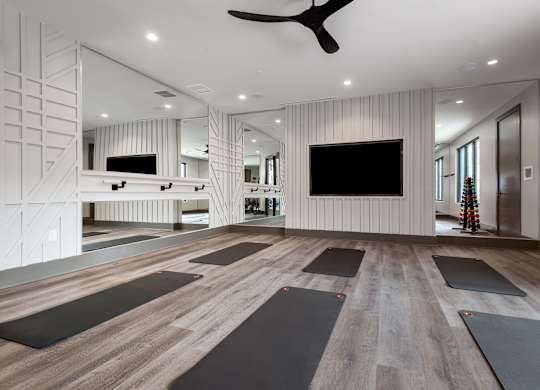 a spacious yoga room with a large flat screen tv on the wall and a row of yoga