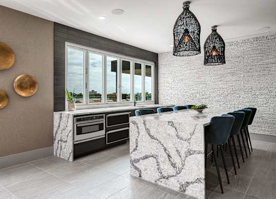 a kitchen with white marble countertops and a long island with blue chairs
