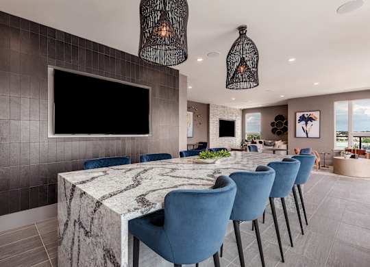 a long table with blue chairs and a large television on the wall