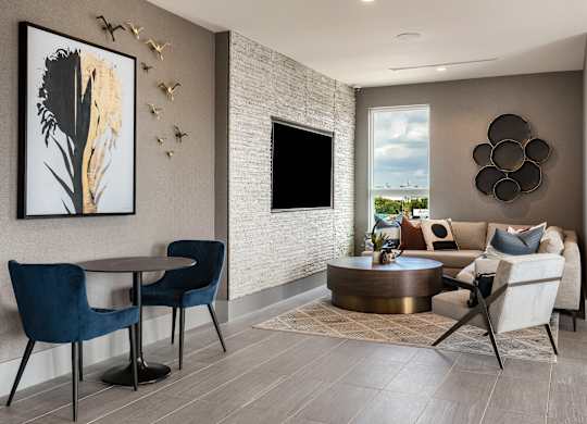 a living room with a couch table and chairs and a flat screen tv on the wall