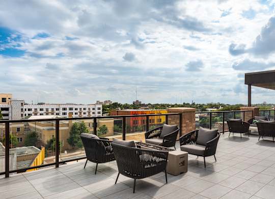 a large terrace with chairs and a table with a view of the city in the background