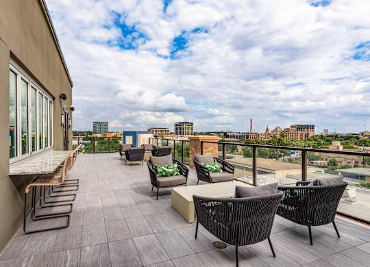 an outdoor terrace with chairs and couches with a view of the city